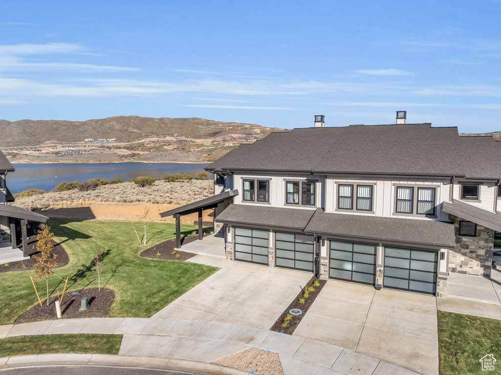 View of front facade with a water and mountain view, a front yard, and a garage