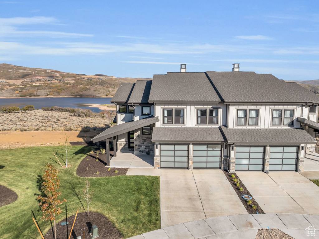 View of front facade featuring a mountain view, a front yard, and a garage