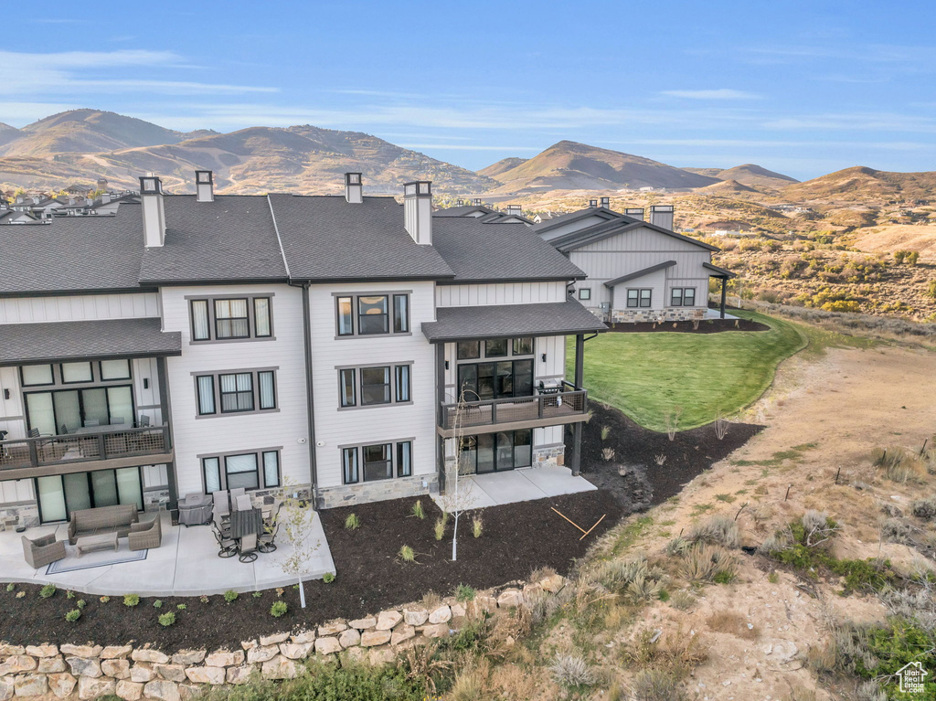 Rear view of property featuring a patio, an outdoor living space, a mountain view, and a yard