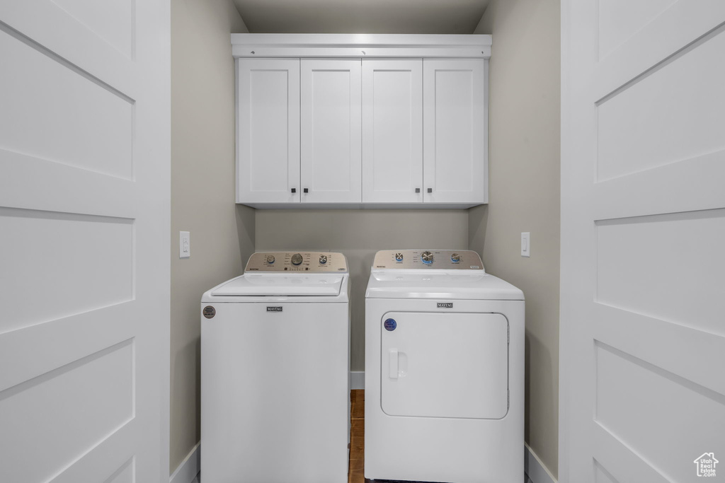 Washroom featuring cabinets and washing machine and clothes dryer