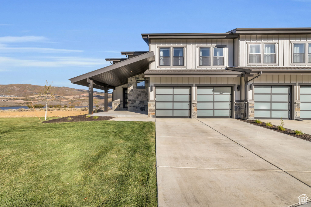 View of front of property featuring a mountain view, a front yard, and a garage