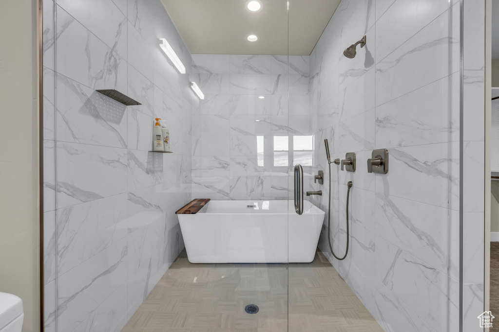 Bathroom featuring shower with separate bathtub and tile walls