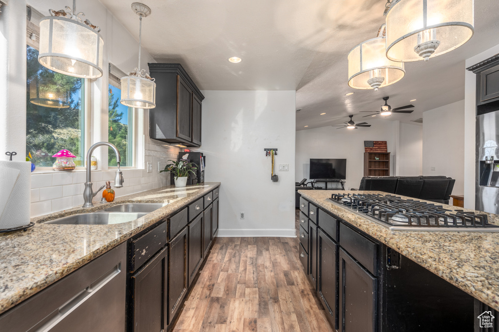 Kitchen featuring lofted ceiling, light hardwood / wood-style flooring, sink, pendant lighting, and tasteful backsplash