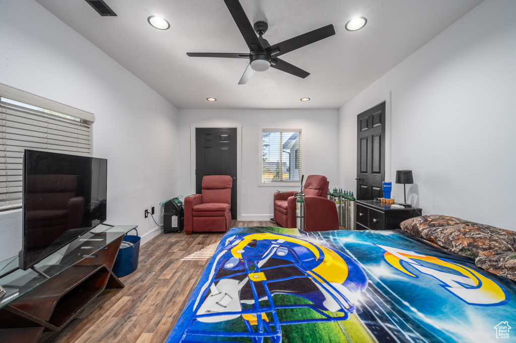 Bedroom with a brick fireplace, dark wood-type flooring, and ceiling fan