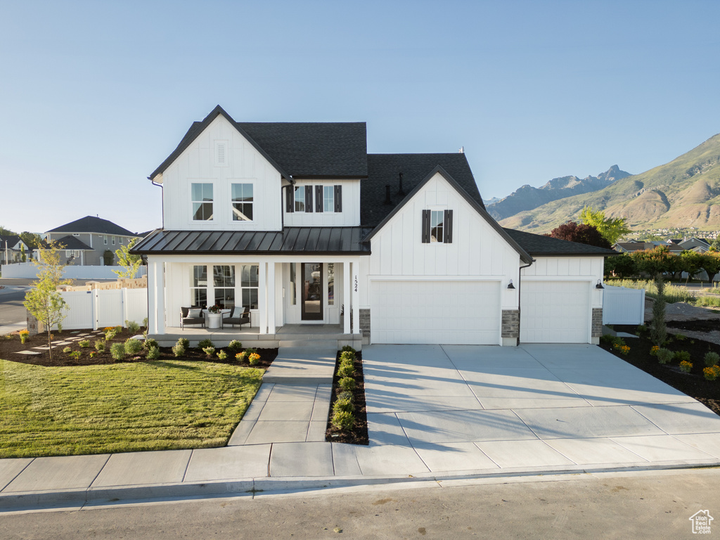 Modern farmhouse style home with a mountain view, a porch, a front lawn, and a garage