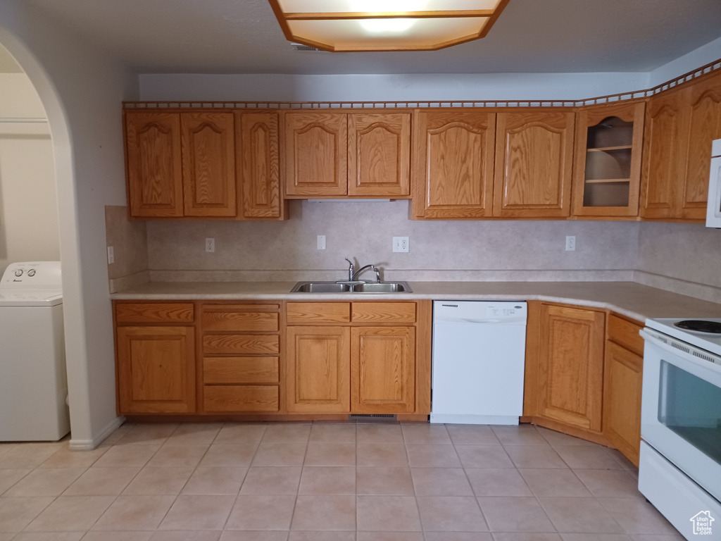 Kitchen featuring sink, light tile patterned flooring, white appliances, and washer / clothes dryer