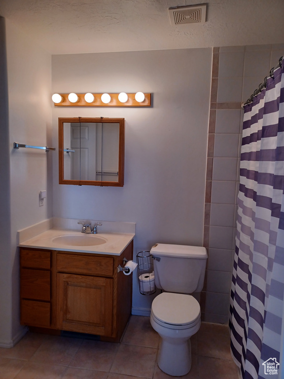 Bathroom featuring toilet, curtained shower, vanity, and tile patterned floors