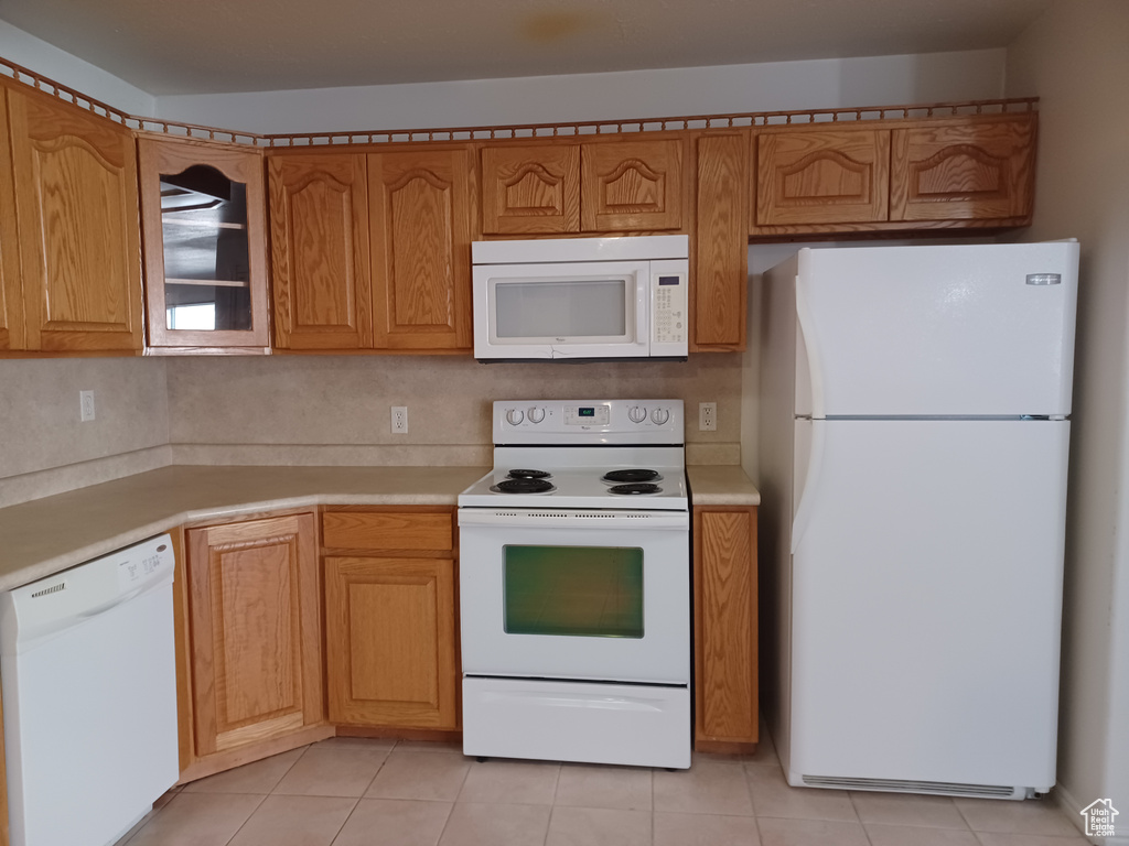 Kitchen with decorative backsplash, light tile patterned flooring, and white appliances