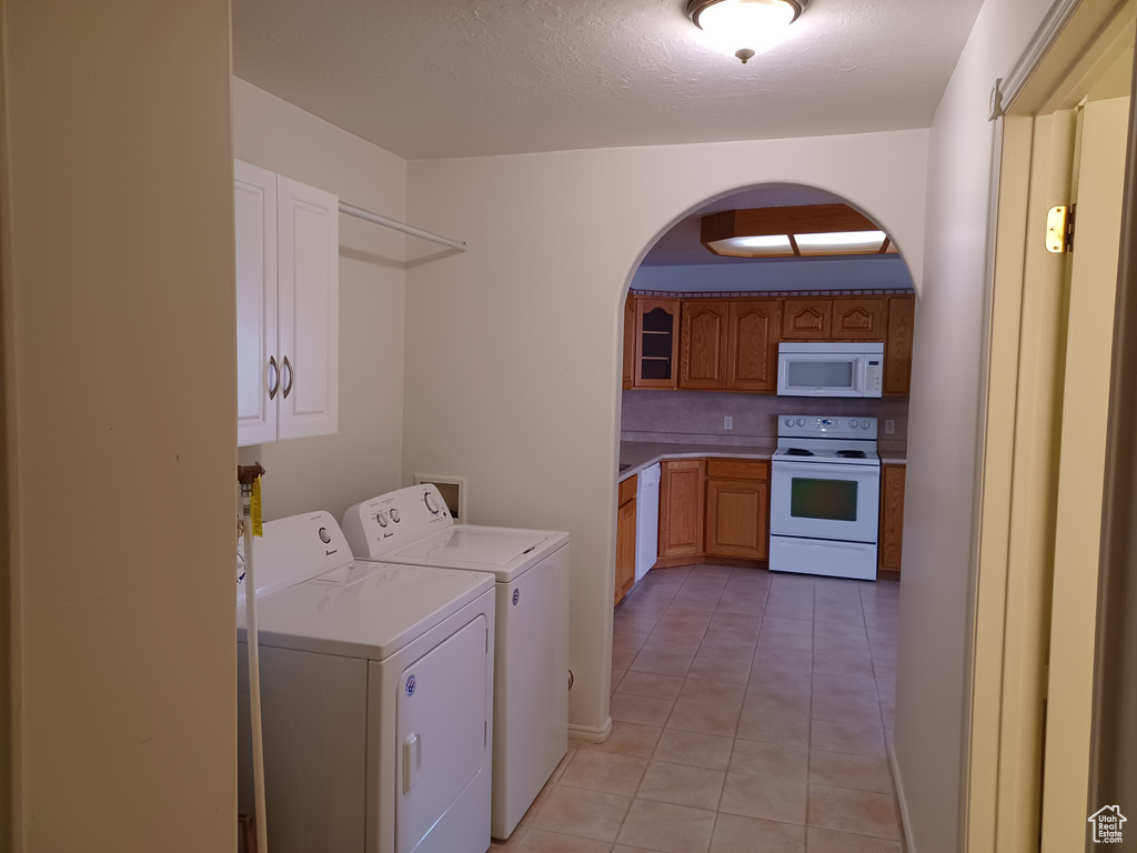 Laundry room with a textured ceiling, washing machine and dryer, and light tile patterned floors