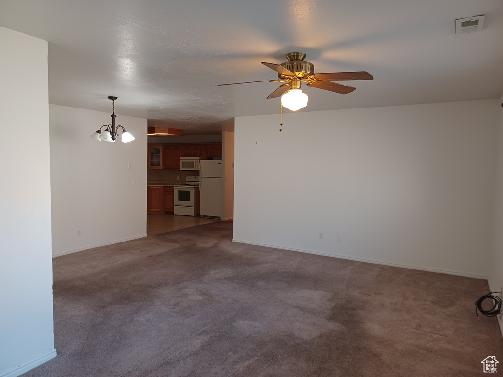 Carpeted empty room featuring ceiling fan with notable chandelier