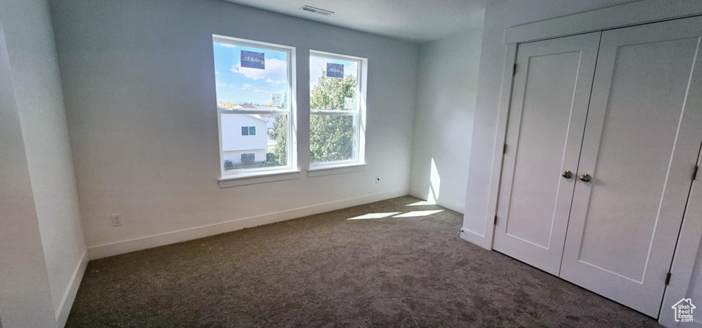 Unfurnished bedroom featuring dark carpet