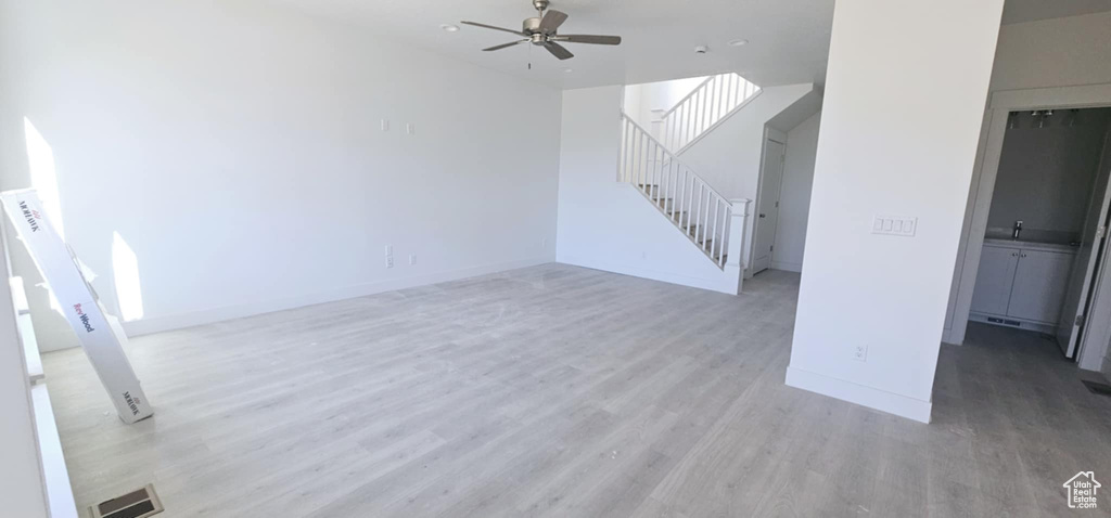 Unfurnished living room featuring ceiling fan and light wood-type flooring