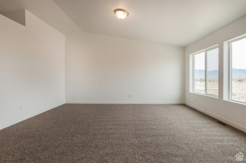 Carpeted empty room with lofted ceiling and a mountain view