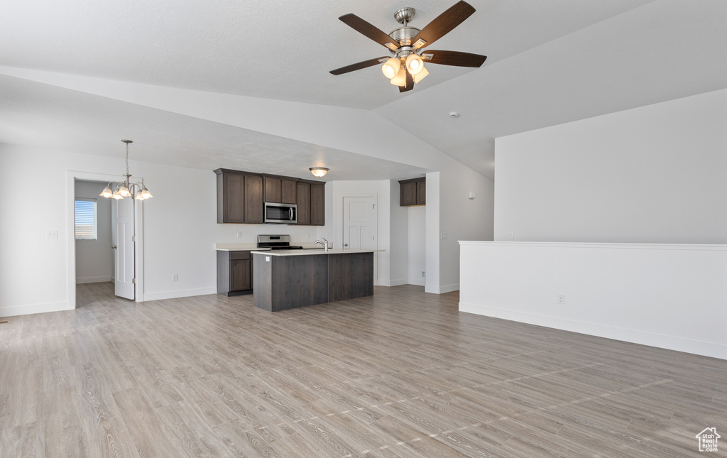 Interior space with dark brown cabinets, ceiling fan with notable chandelier, lofted ceiling, light hardwood / wood-style flooring, and stainless steel appliances