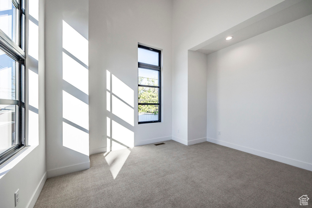 Unfurnished room with light colored carpet and a high ceiling