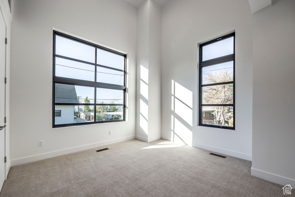 Spare room with light carpet and a towering ceiling