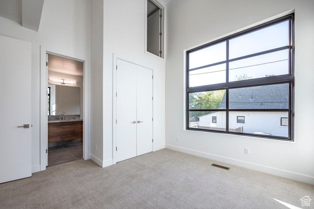 Unfurnished bedroom with connected bathroom, light carpet, and sink