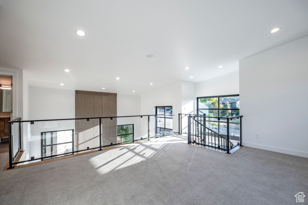 Carpeted empty room featuring vaulted ceiling