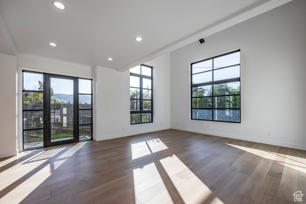 Empty room with a mountain view, wood-type flooring, and plenty of natural light