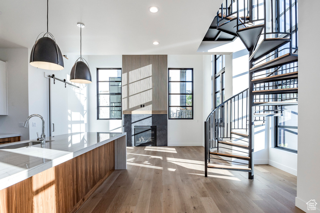 Kitchen with a tiled fireplace, a barn door, sink, light hardwood / wood-style floors, and decorative light fixtures