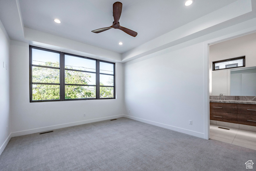 Empty room featuring light carpet, sink, and ceiling fan