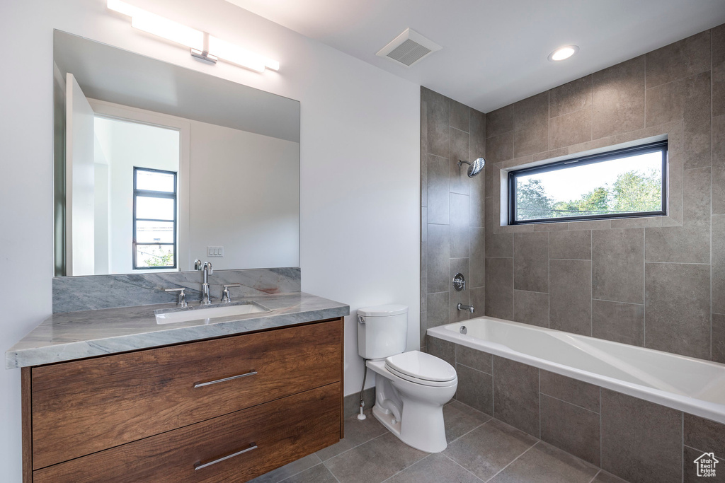 Full bathroom with vanity, toilet, a healthy amount of sunlight, and tiled shower / bath