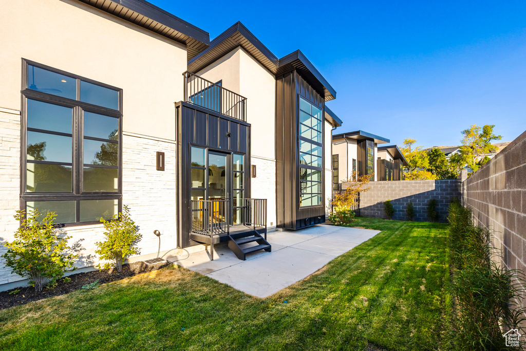 Back of house with a balcony and a yard