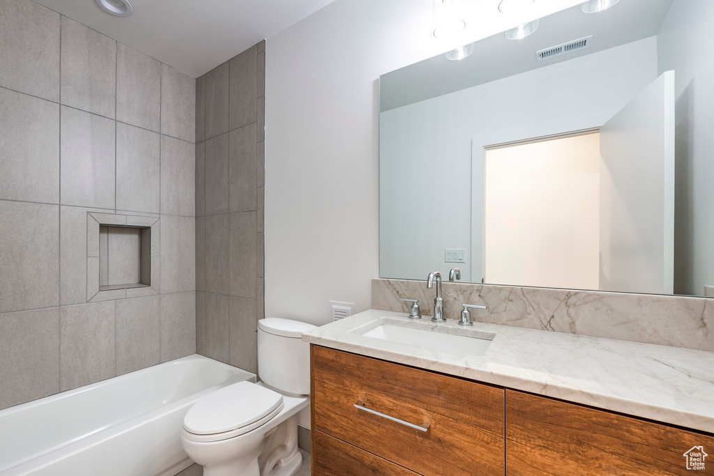 Full bathroom featuring vanity, tiled shower / bath, and toilet