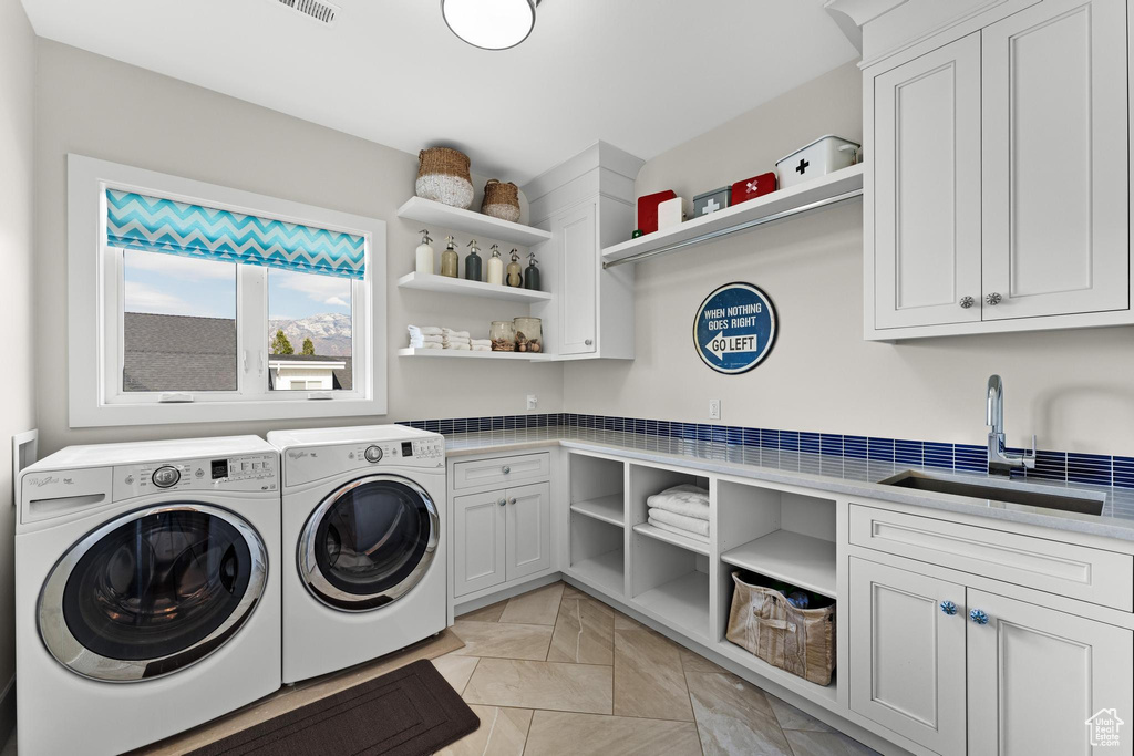 Laundry area featuring cabinets, sink, and washing machine and clothes dryer