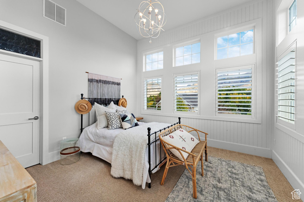 Bedroom with light carpet, multiple windows, and an inviting chandelier