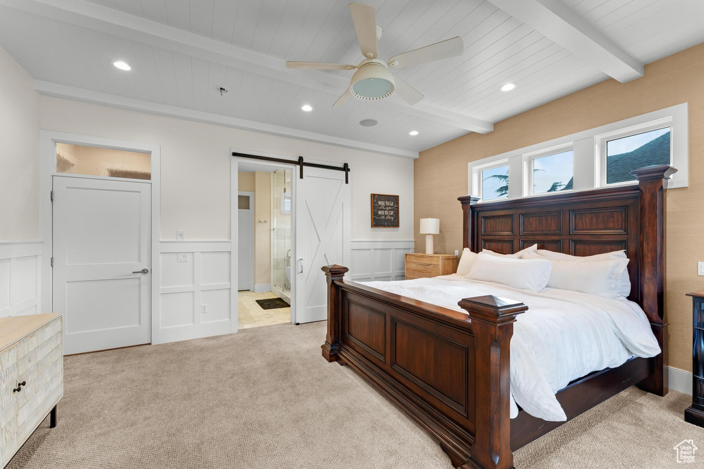 Bedroom featuring light carpet, beam ceiling, a barn door, and ceiling fan