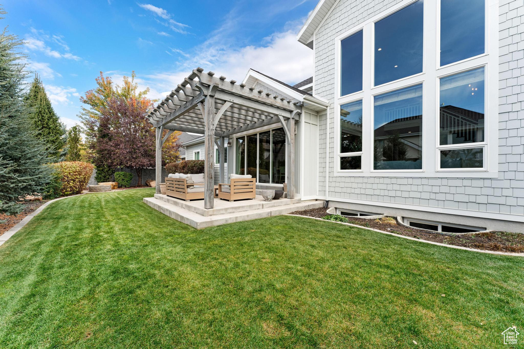 Back of property featuring a patio, a lawn, and a pergola