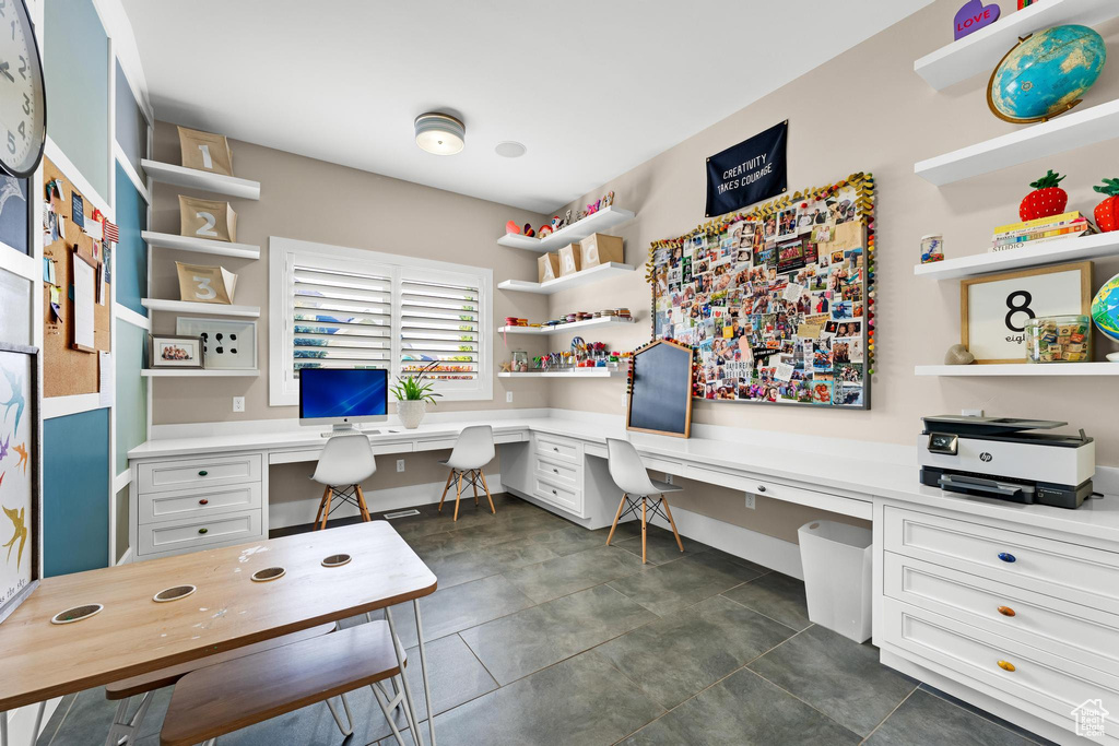 Office area with built in desk and dark tile patterned floors