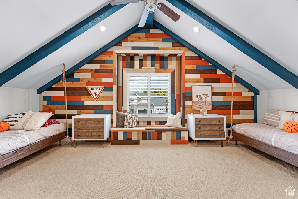 Additional living space with carpet, lofted ceiling with beams, ceiling fan, and wood walls