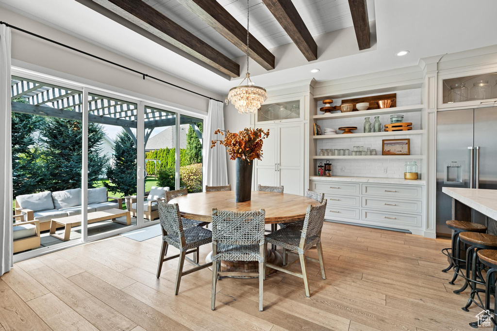 Dining area with light hardwood / wood-style flooring, a chandelier, and beamed ceiling