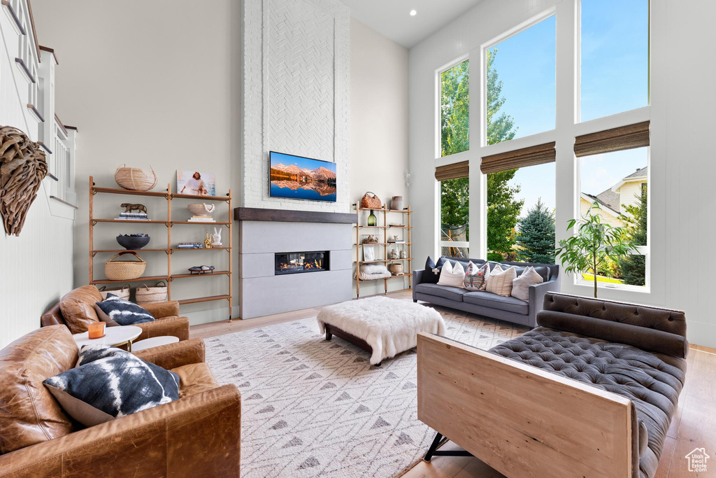 Living room featuring a large fireplace, a high ceiling, and light wood-type flooring