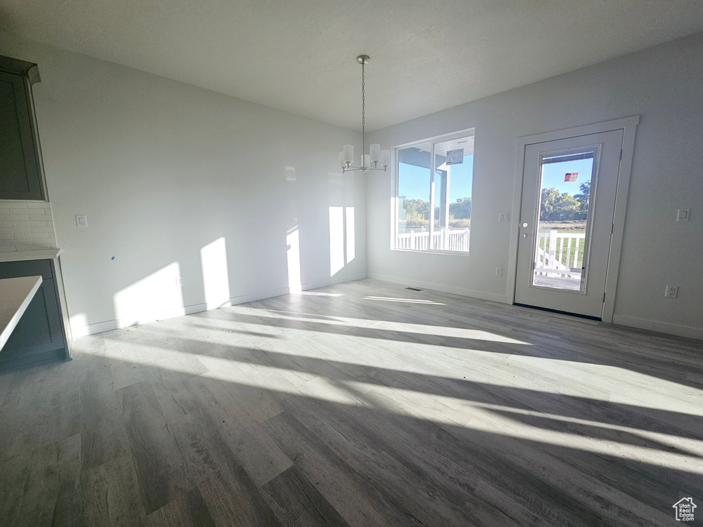 Unfurnished dining area featuring a chandelier and wood-type flooring