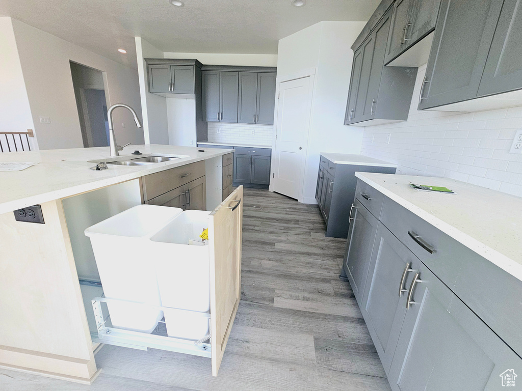 Kitchen featuring sink, decorative backsplash, gray cabinetry, and light hardwood / wood-style floors