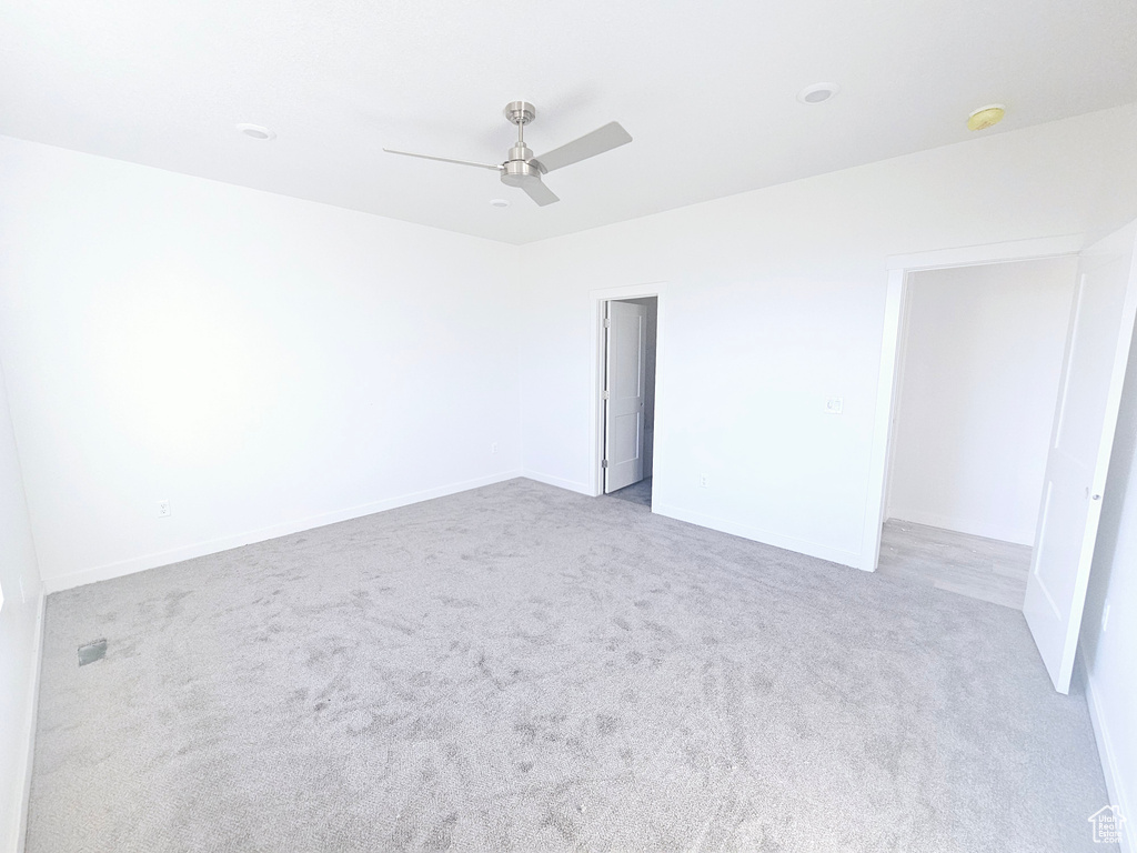 Empty room with light colored carpet and ceiling fan