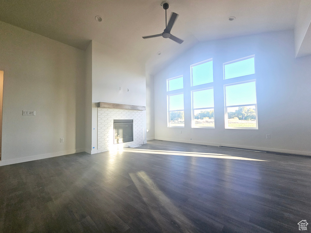 Unfurnished living room with ceiling fan, lofted ceiling, a fireplace, and dark hardwood / wood-style flooring