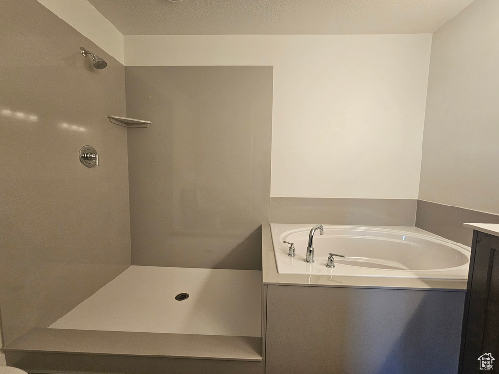 Bathroom with vanity, a textured ceiling, and shower with separate bathtub