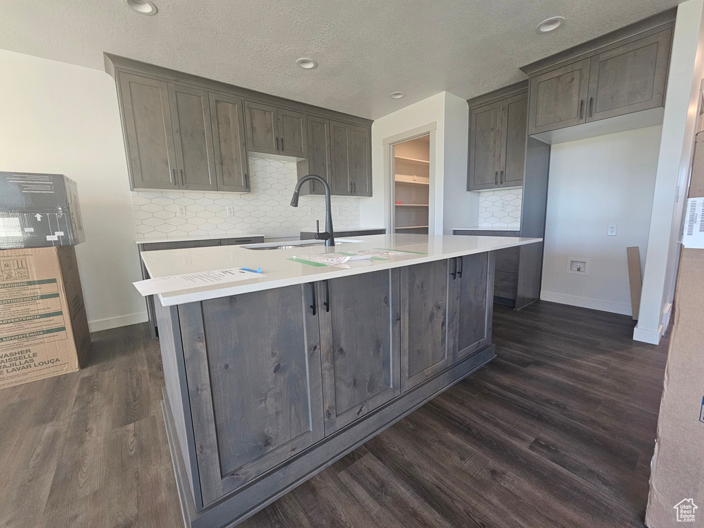 Kitchen with decorative backsplash, sink, an island with sink, and dark hardwood / wood-style floors