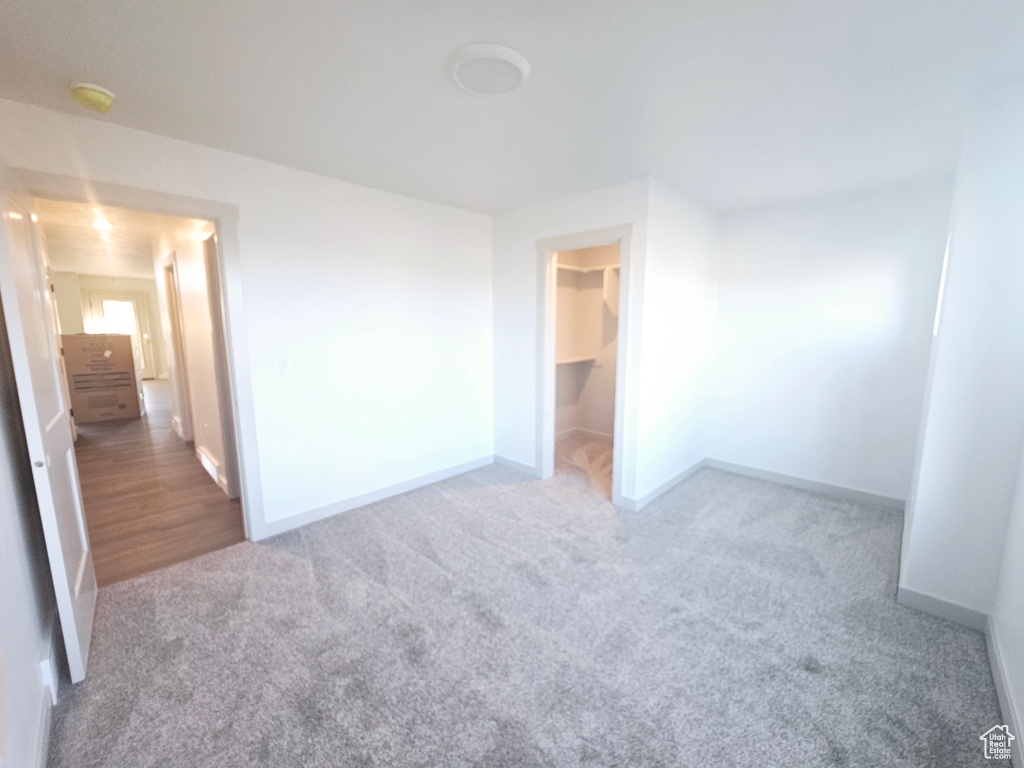 Unfurnished bedroom featuring a walk in closet, a closet, and carpet flooring