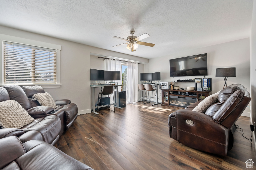 Living room with ceiling fan, a textured ceiling, and dark hardwood / wood-style flooring