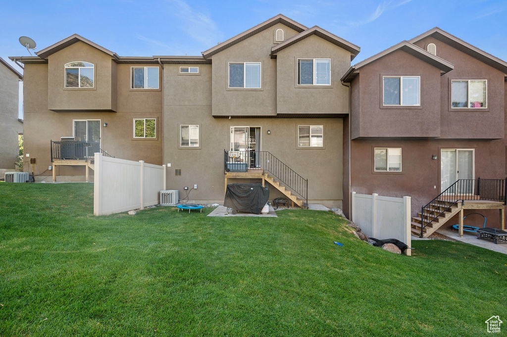 Rear view of property featuring a yard and central AC