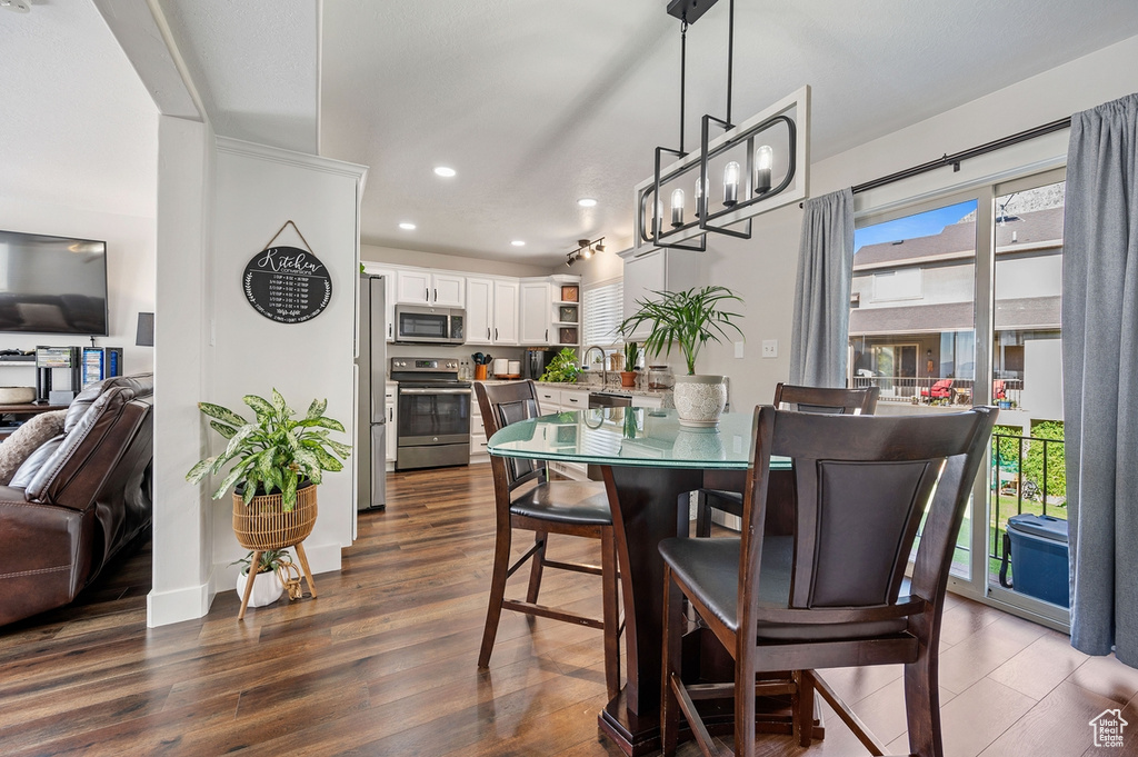 Dining area with sink, dark wood-type flooring, and a notable chandelier