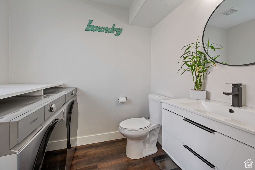 Bathroom with vanity, toilet, wood-type flooring, and washer and clothes dryer