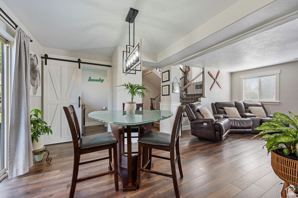 Dining space with dark hardwood / wood-style floors, a barn door, and a textured ceiling