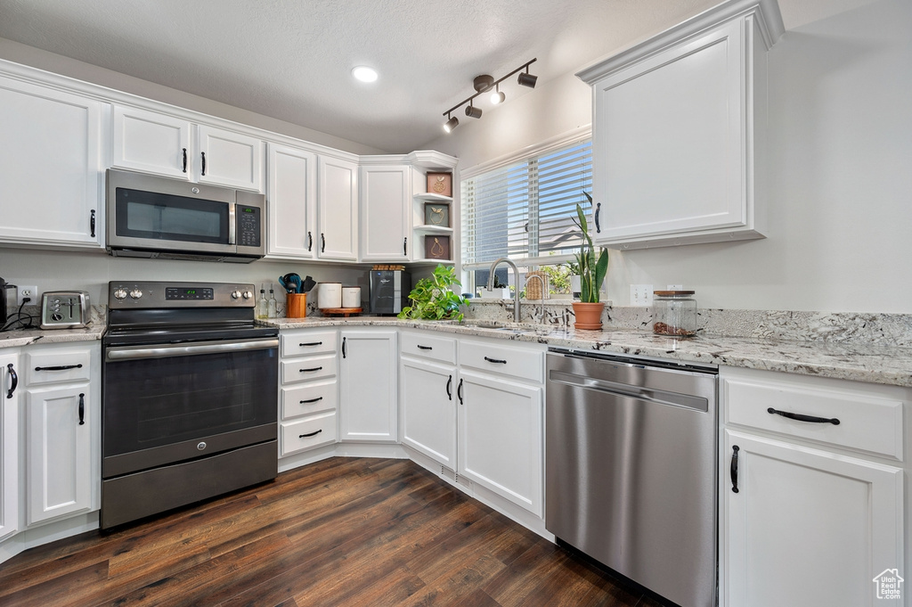 Kitchen featuring appliances with stainless steel finishes, white cabinetry, sink, and dark wood-type flooring