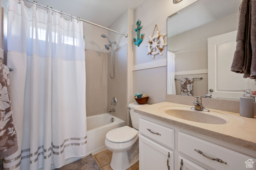 Full bathroom featuring vanity, shower / bath combo with shower curtain, toilet, and tile patterned flooring